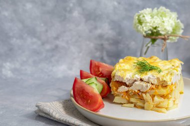 Tavuk göğsü, havuç ve soğanlı patates güveci. Peynirle kaplanmış. Taze sebzelerle süslenmiş. Ama gri bir arkaplan. Boşluğu kopyala.