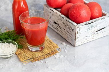 Cam bardaklarda domates suyu ve taze domates. Açık gri arka planda. Vitamin içeceği. Dereotu filizi ve kaba tuzla süslenmiş. Boşluğu kopyala
