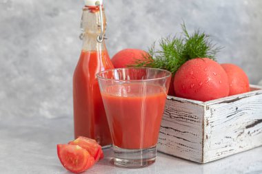 Cam bardaklarda domates suyu ve taze domates. Açık gri arka planda. Vitamin içeceği. Dereotu filizi ve kaba tuzla süslenmiş. Boşluğu kopyala