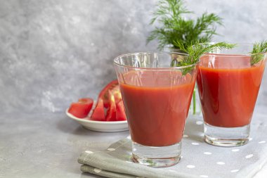 Cam bardakta domates suyu. Açık gri arka planda. Vitamin içeceği. Dereotuyla süslenmiş olarak. Boşluğu kopyala.