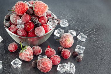 Donmuş meyveler. Frenk üzümü, kiraz ve çilek karışımı dondurulmuş meyve. Vitamin karışımı. Karanlık bir arka planda. Boşluğu kopyala.