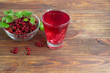 Kırmızı frenk üzümü ve yeşil yapraklar koyu bir arka planda. Vitamin kokteyli. Boşluğu kopyala