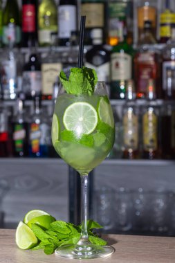 Limonlu ferahlatıcı bir yaz kokteyli. Alkolik içki. Bir tutam nane ve buz ile süslenmiş. Barda. Önplan.