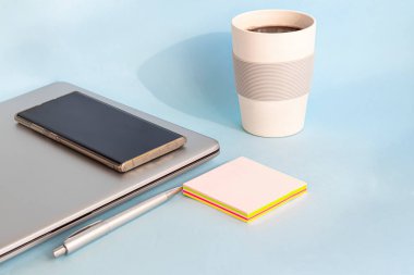 Karantina, online eğitim, evden çalışma. Laptop, telefon ve kalem, etiketler ve kahve yeniden kullanılabilir bardakta. Dünyada koronavirüs salgını. Ofisleri ve okulları kapatıyorum. Boşluğu kopyala.