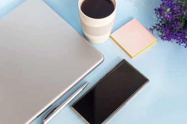 Karantina, online eğitim, evden çalışma. Laptop, telefon ve kalem, etiketler ve kahve yeniden kullanılabilir bardakta. Dünyada koronavirüs salgını. Ofisleri ve okulları kapatıyorum. Boşluğu kopyala.