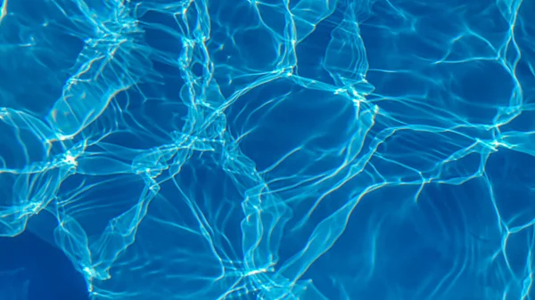 Havuzdaki su mavidir, güneş ışınları tarafından nüfuz edilir. Seçici odaklanma. Sağlıklı bir yaşam tarzı. Çocuklar için Tatil.