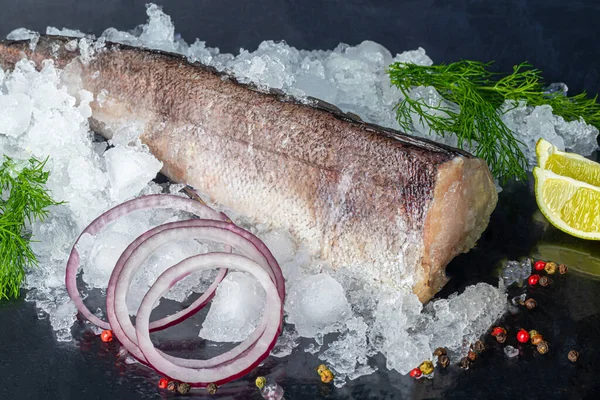 Taze donmuş hake leşi. Mutfak malzemeleri, bitkiler, biber ve limonlu siyah arka planda balık filetosu. Boşluğu kopyala