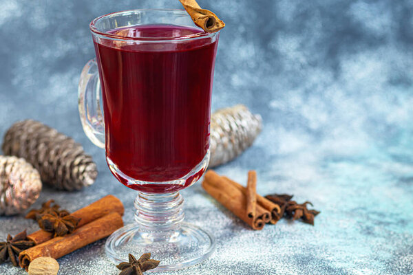 Mulled wine, a warming drink in a cup with spices. Christmas toys. New Year mood. On a light background. Copy space.