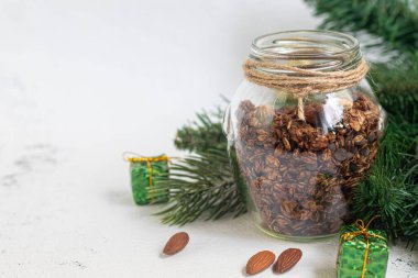 Cam kavanozda çikolata ve fındıklı ev yapımı granola. Yeni yıl konsepti. Gri bir arka planda. Vejetaryen yemeği. Boşluğu kopyala.