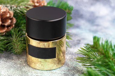 Parfüm şişesi. Noel ağacı dalları ve Noel oyuncaklarıyla çevrili. Yeni yıl ve Noel için hediye konsepti. Hafif bir arkaplanda. Boşluğu kopyala.
