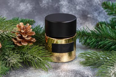 Parfüm şişesi. Noel ağacı dalları ve Noel oyuncaklarıyla çevrili. Yeni yıl ve Noel için hediye konsepti. Hafif bir arkaplanda. Boşluğu kopyala.