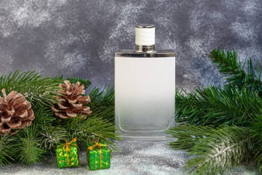 Parfüm şişesi. Noel ağacı dalları ve Noel oyuncaklarıyla çevrili. Yeni yıl ve Noel için hediye konsepti. Hafif bir arkaplanda. Boşluğu kopyala.