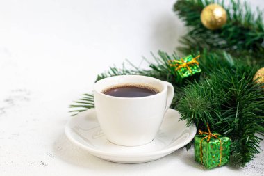 Bir fincan lezzetli aromatik kahve. Kahve çekirdeklerinden yapılmış bir substrat üzerine yerleştirilmiştir. Yeni yıl tatili konsepti. Hafif bir arkaplanda. Boşluğu kopyala.