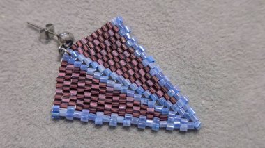 Hafif arka planda el yapımı boncuklu ve cam boncuklu küpeler. Ürün gösterisi. Moda trendleri. Boşluğu kopyala