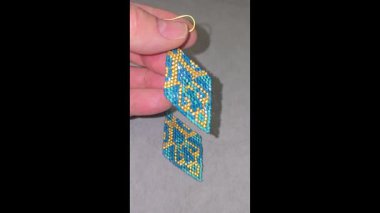 Hafif arka planda el yapımı boncuklu ve cam boncuklu küpeler. Ürün gösterisi. Moda trendleri. Boşluğu kopyala