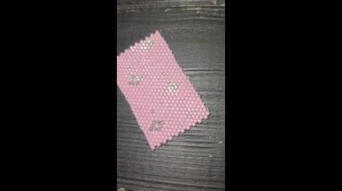 A pink handmade bracelet made of Japanese beads on a light background. Decor: glass bead weaving.