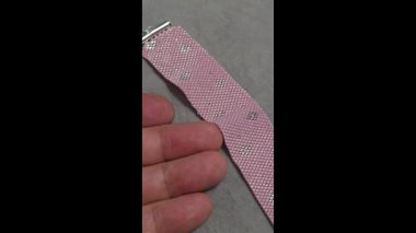 A pink handmade bracelet made of Japanese beads on a light background. Decor: glass bead weaving.
