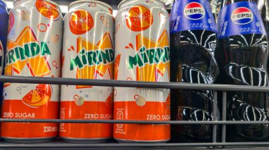 Bottles of Pepsi-Cola and Mirinda on a store counter and in a customer's hand. Sweet drinks for sale. Supermarket display.