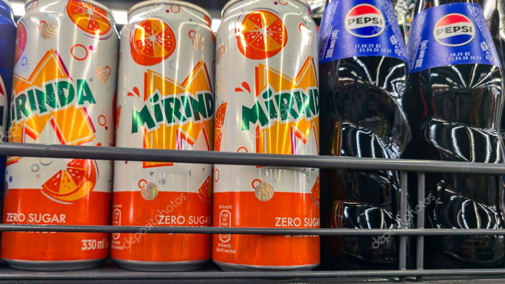 Bottles of Pepsi-Cola and Mirinda on a store counter and in a customer's hand. Sweet drinks for sale. Supermarket display.