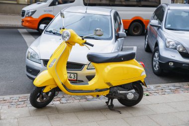City Riga, Letonya. Retro Scooter Vespa Street, sarı renk. Kentsel şehir manzaralı. 2018.