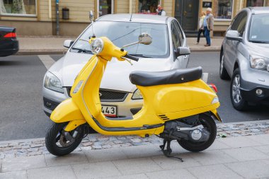 City Riga, Letonya. Retro Scooter Vespa Street, sarı renk. Kentsel şehir manzaralı. 2018.