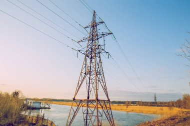 Elektrik Kulesi ve nehir. Güneşli gün ve eski demir inşaat