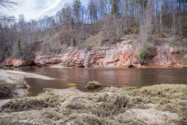  Kırmızı kayalar ve Gauja Nehri. İlkbaharda doğa ve güneş. 2019.