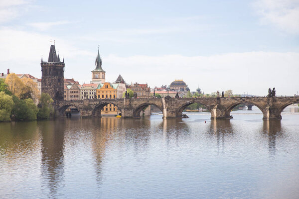 Old Charles bridge and buildings. Vltava river with glare. Trave