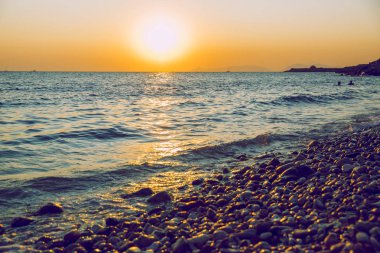 Yunan Cumhuriyeti. Denizde güneş ışığı ve yüzen insanlar. Dist olarak