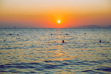 Yunan Cumhuriyeti. Denizde güneş ışığı ve yüzen insanlar. Dist olarak
