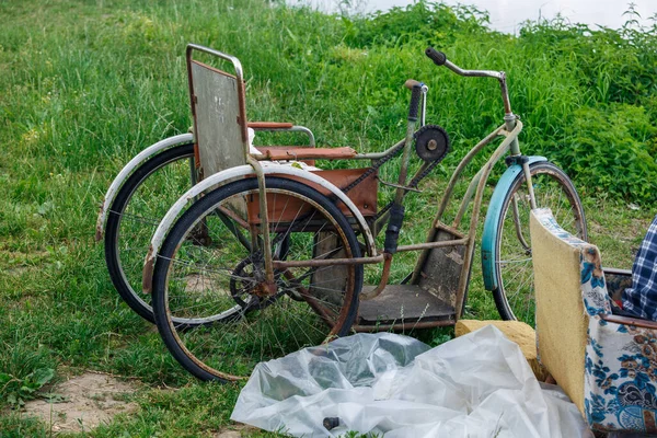 ラトビアの都市プラヴィナス 川の古い錆びた障害者用自転車と緑の芝生 — ストック写真
