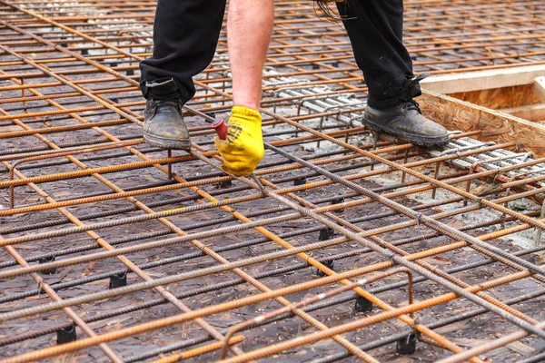 Worker ties steel reinforcing bars with wire.