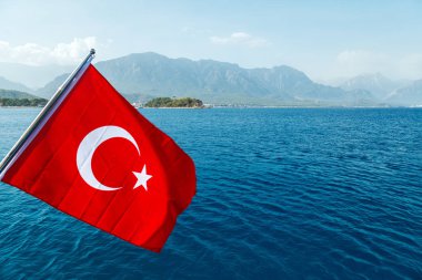 Beyaz bir hilal ve yıldız ile kırmızı bir Türk bayrağı rüzgara karşı inanılmaz bir deniz manzara fon tarafından geliştirmektedir. Akdeniz ve Türkiye sahillerinde içinde belgili tanımlık geçmiş