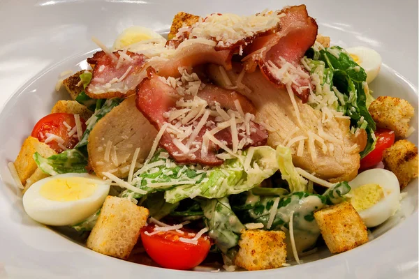 Popular North American Caesar Salad with Chicken, Eggs and Parmesan, Croutons and Tomatoes in Mild Garlic-Mustard Sauce. Close up