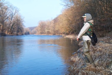 Çekici bir kadın bir nehir kıyısında ayakta açık bahar güneşli bir günde bir iplik ile balık yakalar