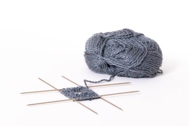 Dört örgü iğnesine örmeye başla. Örgü yün ve örgü iğneleri beyaz arka planda izole edilmiş..