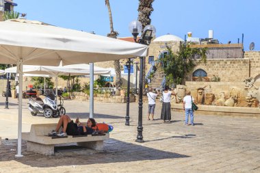 Tel Aviv, İsrail - 17 Eylül 2017: Huzursuz bir genç kadın eski eserler Meydanı eski Jaffa'nda bir tente altında bir bankta dinleniyor.