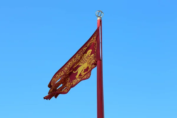 This is the flag of Venice with the winged lion of the Evangelist Mark raised on a flagpole.