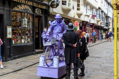 YORK GREAT BRITAIN - 9 Eylül 2014: Tanımlanamayan kişiler, eski şehir caddesinde yaşayan bir heykeli resmeden bir sokak sanatçısının yanındalar.