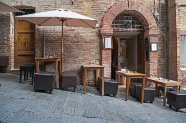 SIENA, İtalya - 14 Eylül 2018 Bunlar ortaçağ şehrinin sokaklarından birinin dik yamacında yer alan bir kafenin masa ve sandalyeleri..