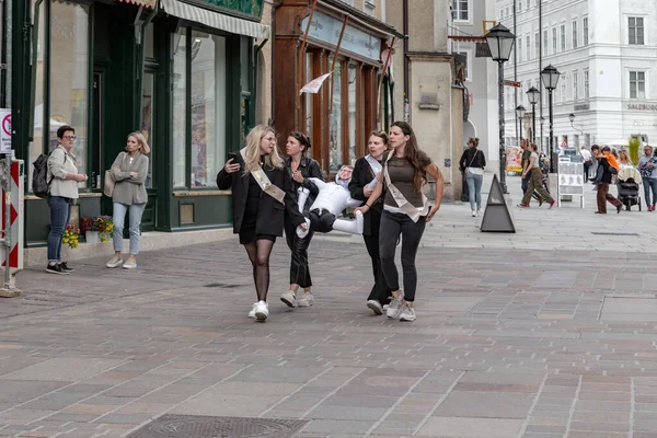 SALZBURG, AUSTRIA - 24 Mayıs 2024: Tanımlanamayan genç kadınlar, Old Town semtinin sokaklarında bir korkulukla bir partiye gidiyorlar.