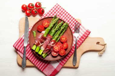 Kuşkonmaz ile jambon, domates ve yumurta haşlanmış bir kil plaka. Beyaz ahşap arka plan. Hafif diyet kahvaltı. Yukarıdan görüntülemek. 