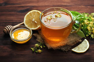 Bir cam fincan koyu ahşap yüzeye kireç çiçekli bitki çayı. Yararlı ve lezzetli içecek. Soğuk algınlığı tedavisi için halk ilaçları. Yan görünüm