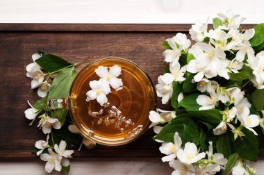 Yasemin bir kahverengi ahşap tahta üzerinde bir cam bardak yeşil çay. Yasemin yanındaki çiçektir. Lezzetli detoks içecek