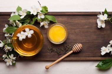 Yasemin bir kahverengi ahşap tahta üzerinde bir cam bardak yeşil çay. Yasemin yanındaki çiçektir. Lezzetli detoks içecek. Metin için yer