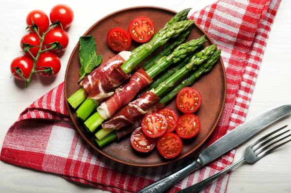 Kuşkonmaz ile jambon, domates ve yumurta haşlanmış bir kil plaka. Hafif diyet kahvaltı ya da akşam yemeği. Yukarıdan görüntülemek. 