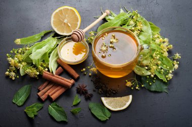 Kireç çiçekler karanlık bir yüzey üzerinde bir cam bardak bitkisel çay. Yararlı ve lezzetli içecek. Soğuk algınlığı tedavisi için halk ilaçları. Yan görünüm