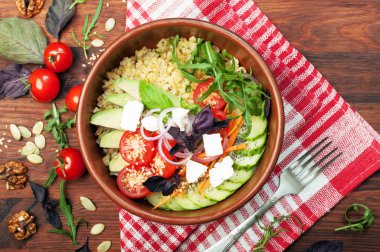 Bulgur, krem peynir, domates, avokado, salatalık, havuç, roka ve fesleğen bir kahverengi ahşap yüzeyde dilimleri ile top. Yararlı ve lezzetli diyet gıda.