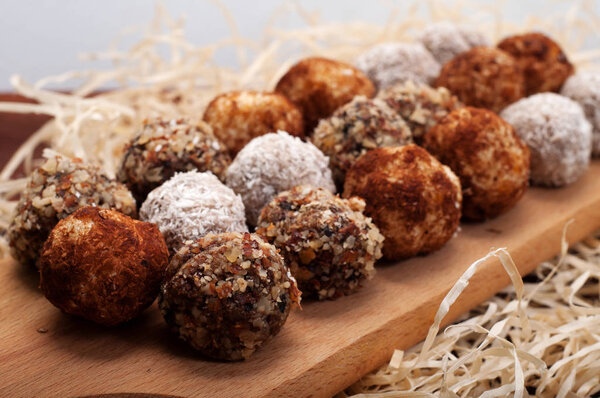 Hand-made sweets made from dried fruits, nuts and seeds (without sugar). Macro shooting. Shallow depth of field, blurred background. Delicious and healthy fitness candy