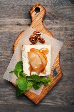 Çiğ gıda tatlı. Hindistan cevizi sütü, kaju fıstığı ve şekersiz şurubu bir yastık tohumlar, kurutulmuş meyve ve fındık yapıştırın. Armut dilimleri ve şurubu üsttedir. Hiçbir pişirme.